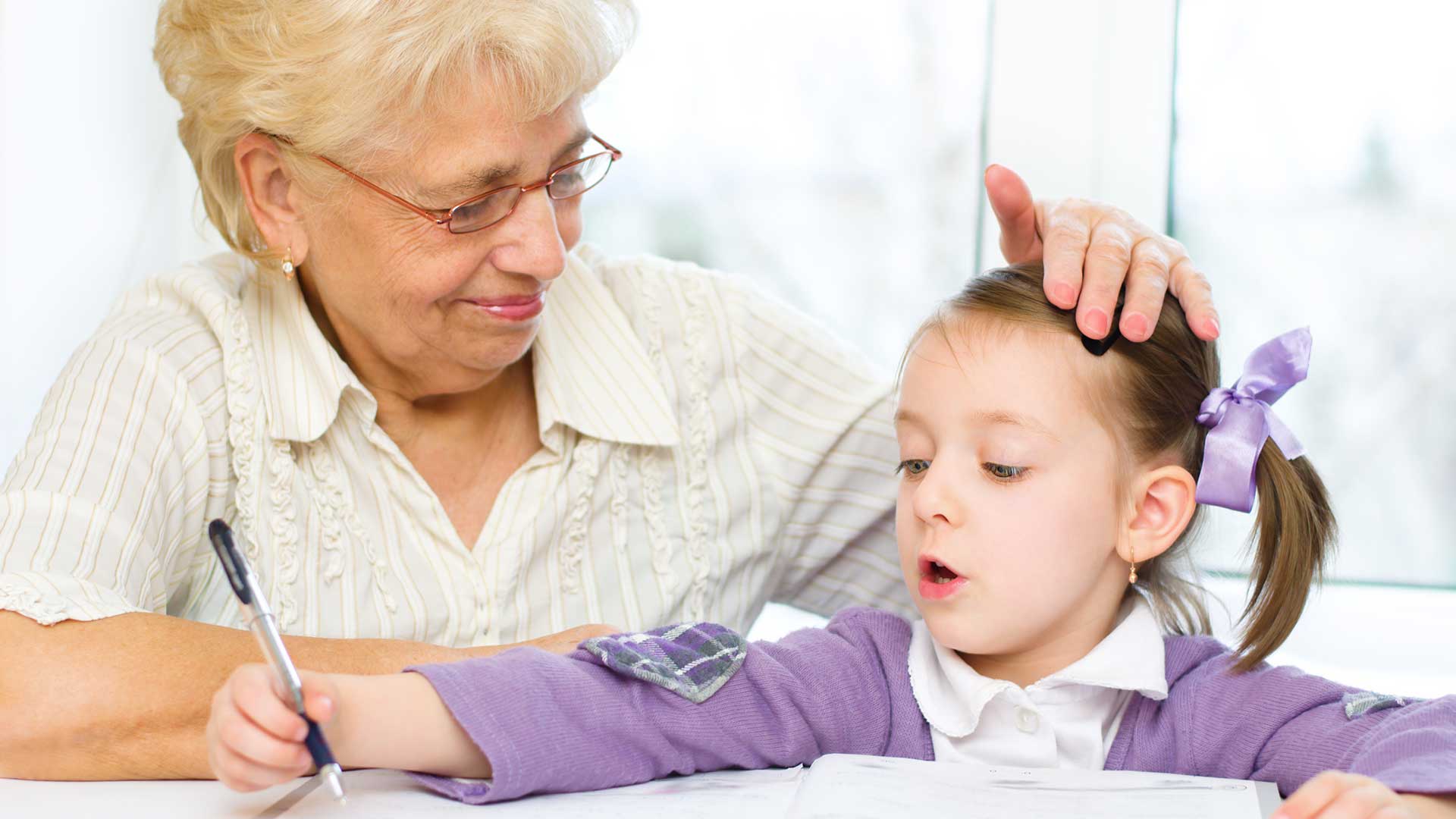 grandmother with granddaughter looking at a book