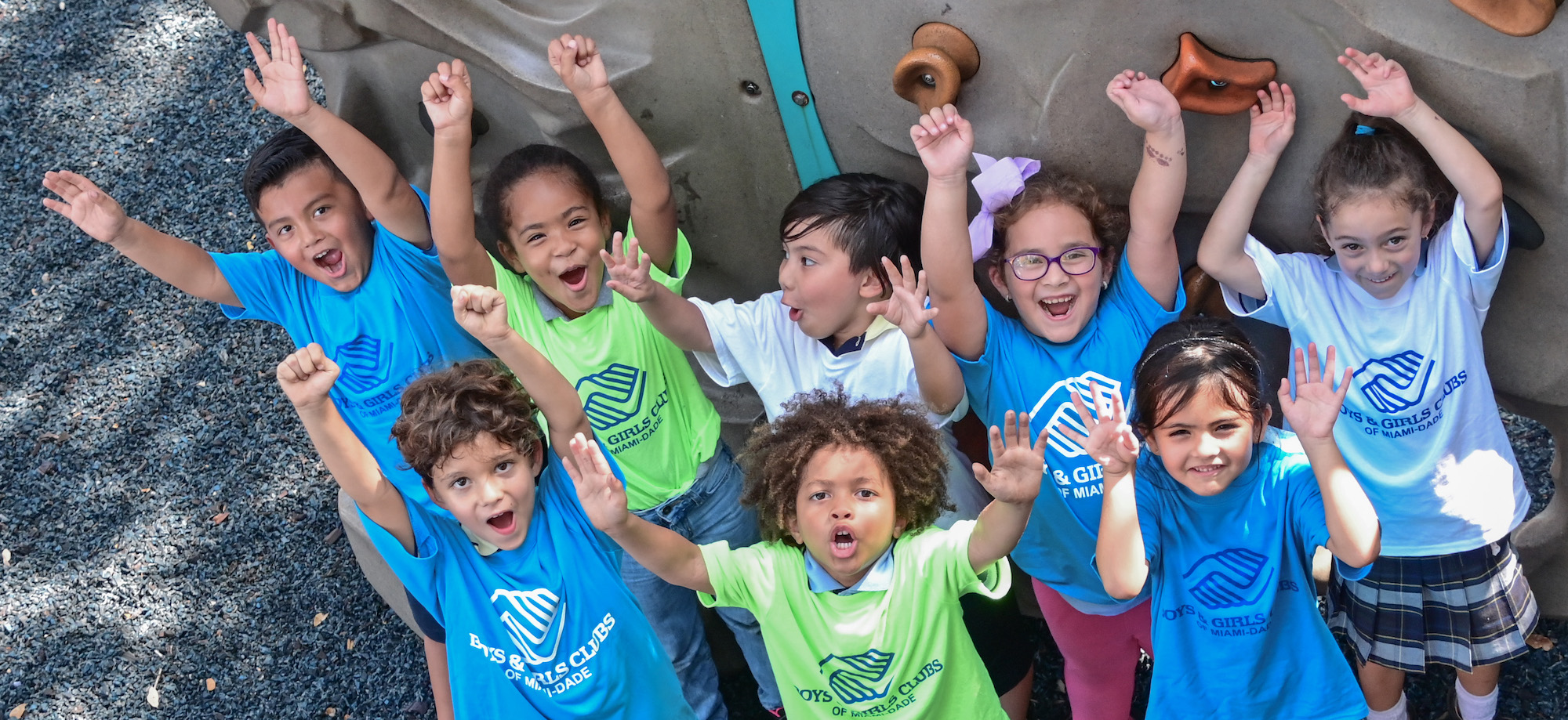 Children in boys and girls club t shirts with their hands up